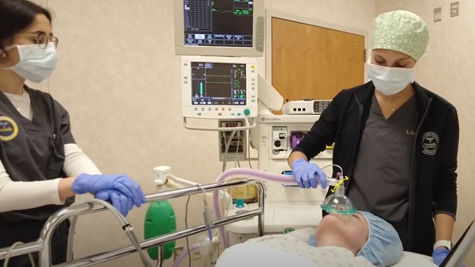 Two anesthesia assistant students training in a classroom environment surrounded by medical equipment