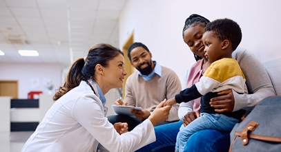 female hospital professional speaking with a young boy and his parents in a hallway