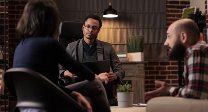 counselor meeting with a man on a couch and woman in a chair in an office