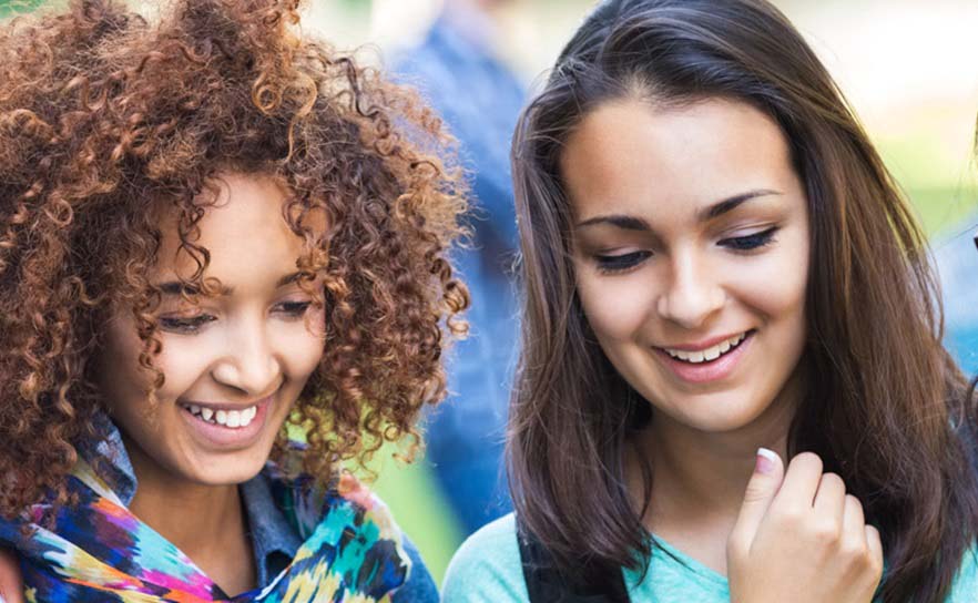 Two women smiling while looking at something