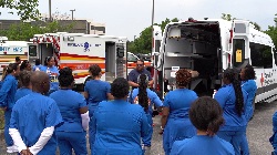 south university physician assistant students listening to a first responder behind several parked ambulance vans