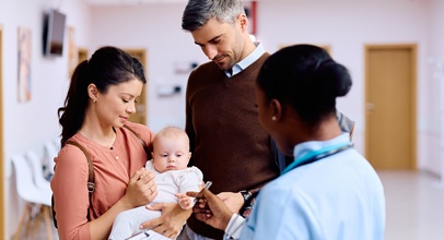 couple holding a baby speaking to their nurse in a hospital