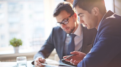 two men discussing what they are looking at on a tablet 