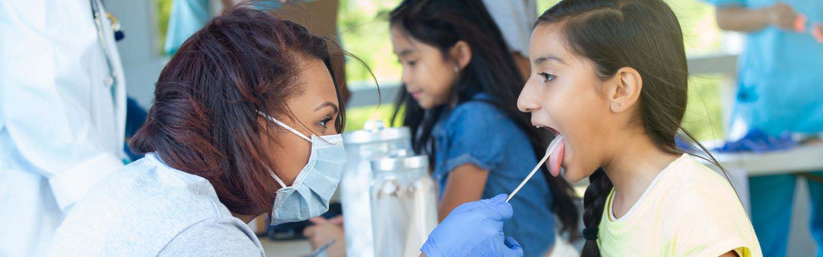 Healthcare worker swabbing child's tongue