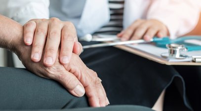 Nurse with hand on older patient's hand-alt-text