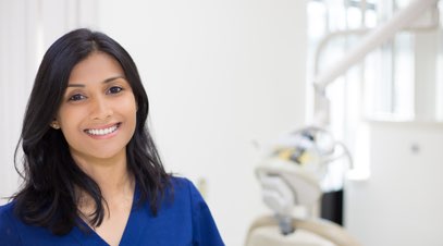 Female nurse smiling in front of medical equipment-alt-text