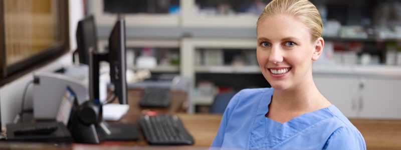 Femaie healthcare adminsitrator sitting at desk smiling