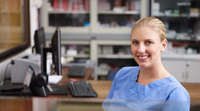 Female healthcare practitioner sitting at desk smiling-alt-text
