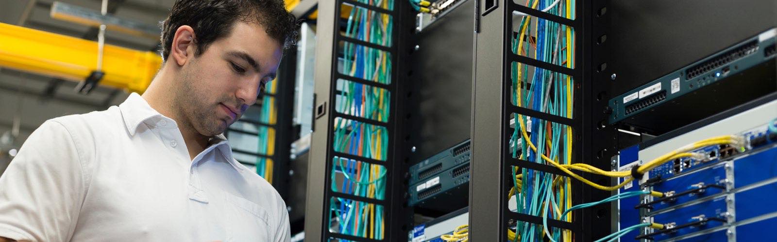 Information technology professional looking at tablet in front of server rack