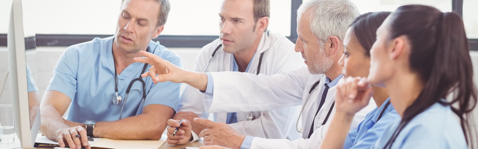 Team of nurses and doctor discussing information on a computer