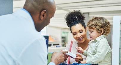 pharmacist helping a woman choose a medicine with her small child nearby