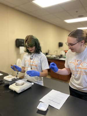 a high school student is practicing a nursing procedure at scrubs camp with a South University rep overseeing