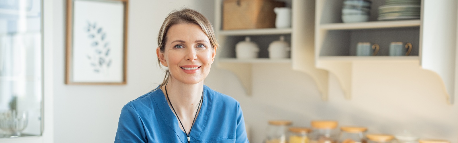 nurse in scrubs sitting at a desk in front of a laptop
